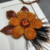 گل تزیینی دست‌ساز نارنجی با منجوق‌دوزی و پرهای طبیعی